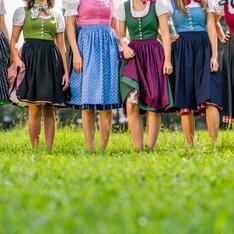 Frauen in bunten Dirndln tanzen auf der grünen Wiese in der Steiermark