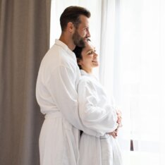 Ein Pärchen kuschelt im stehen im Bademantel