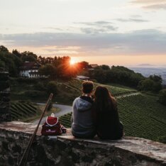 Pärchen sitzt auf Steinmauer der Burg Deutschlandsberg und genießt Ausblick