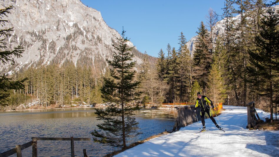 Ein Langläufer zieht seine Runde auf der Loipe um den Grünen See, im Hintergrund der See und die Berge