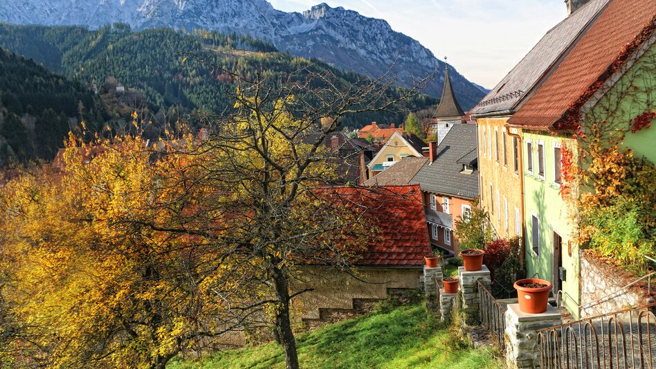 Herbstliche Aufnahme der Kirchenstiege zur Wehrkirche St. Oswald in Eisenerz umgeben von Häusern und Bergen | © M. Pezmann