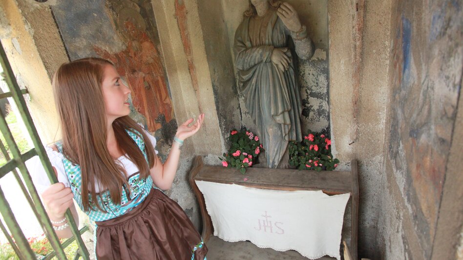 Frau zeigt auf Statue in Kapelle