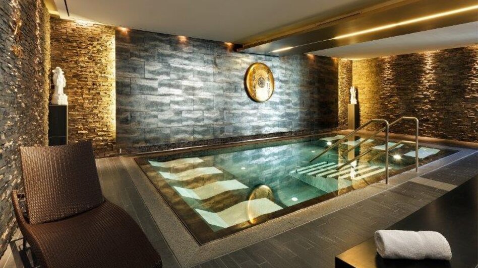 Der Poolinnenbereich im Asia Spa Leoben mit Liegen im Becken