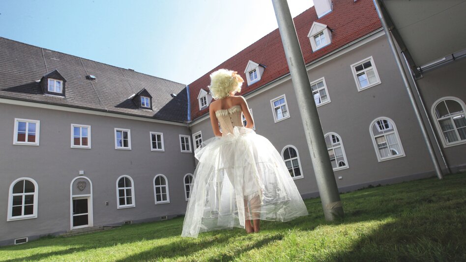 Frau in Kleid steht in einem Klosterinnenhof