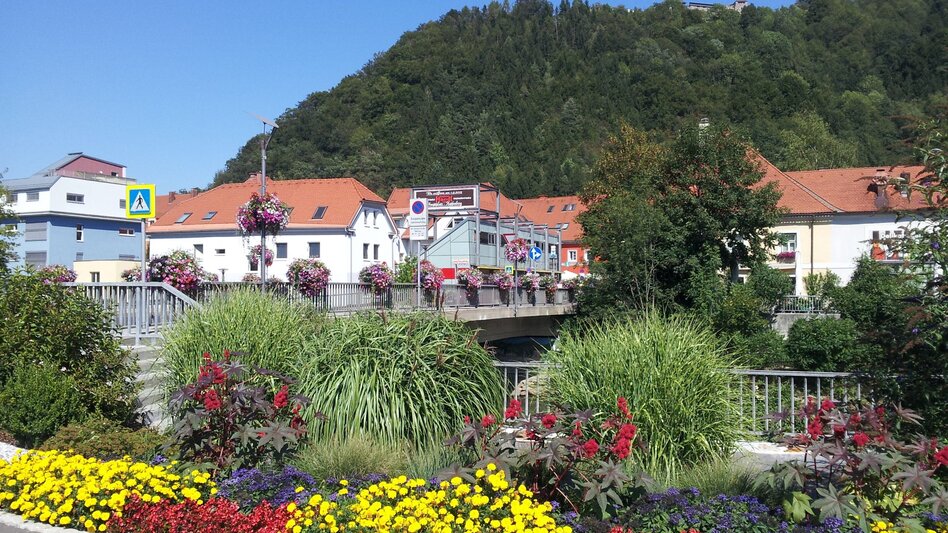 Eine Brücke, davor viele bunte Blumen 