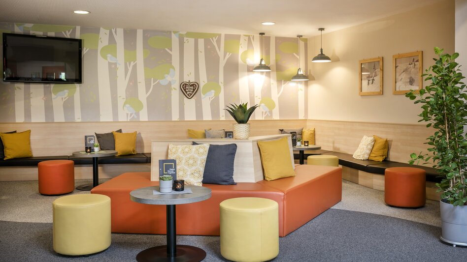 Die Lobby im JUFA Hotel am Sigmundsberg mit mehreren bunten Sitzmöglichkeiten
