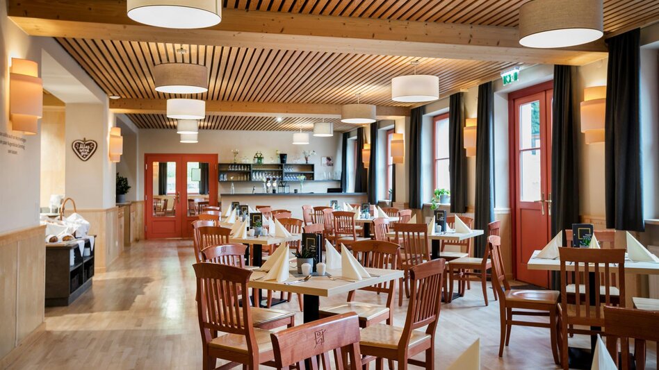 Das Restaurant im JUFA Hotel am Sigmundsberg mit mehreren Tischen und Sesseln