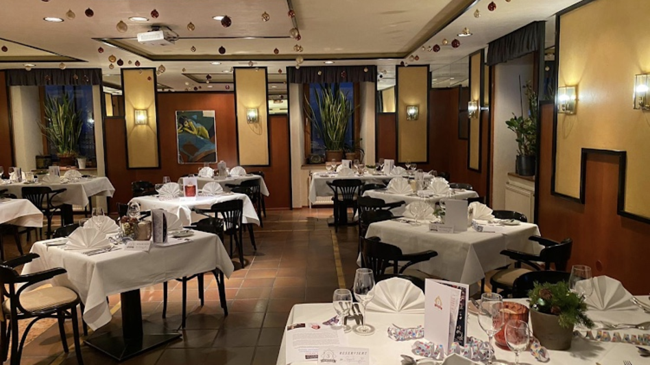Ansicht des Seminarraums im Restaurant Schicker mit schön gedeckten Tischen, Fliesenboden, Bildern an der Wand und Grünpflanzen