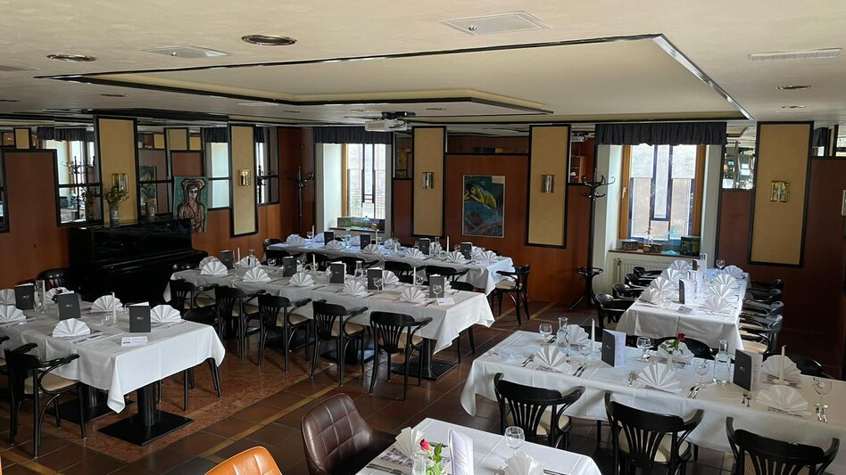 Ansicht des Seminarraums im Restaurant Schicker mit schön gedeckten Tischen, Fliesenboden und Bildern an der Wand