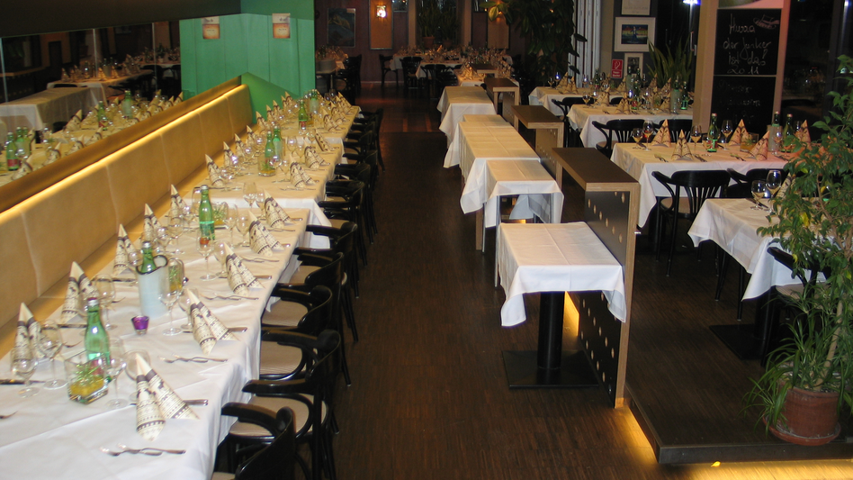 Ansicht des Seminarraums und des Cafe mocca im Restaurant Schicker mit einer langen, schön gedeckten Tafel, viel Dekoration und Blumenschmuck