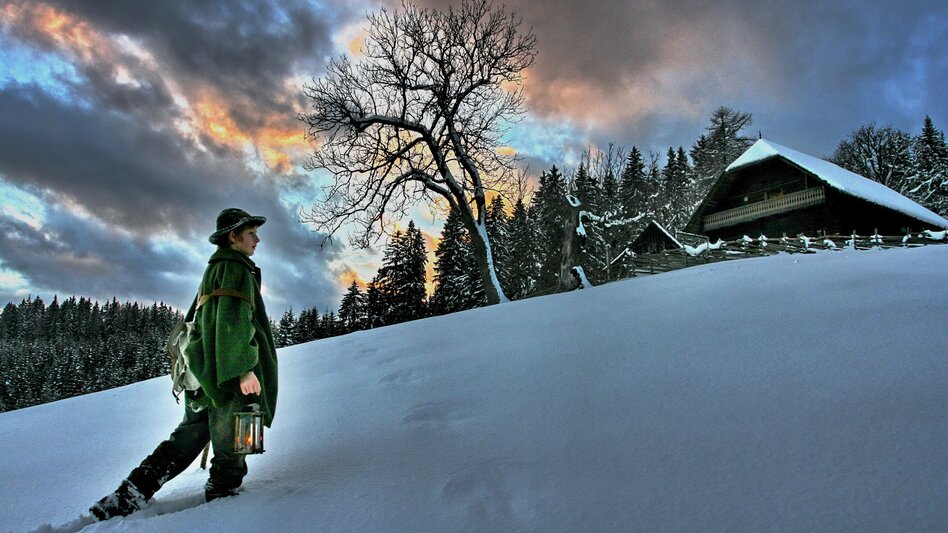 Ein Bub hält eine Laterne in der Hand und stapft durch den Schnee