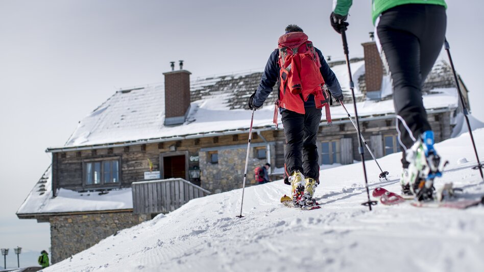 Eine Gruppe von Skitourengehern sind auf den Weg in die urige Berghütte