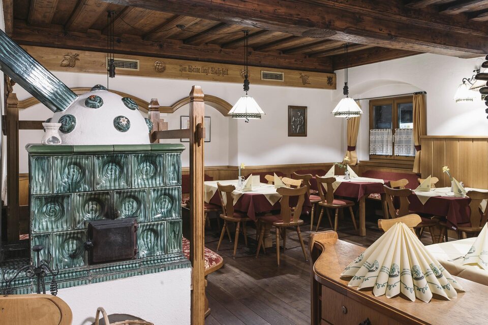 Ein gemütliches Restaurant mit Holzdecke und warmem Ambiente. Die Tische sind liebevoll dekoriert und der Kachelofen verleiht einen rustikalen Charme. | © Stefan Leitner