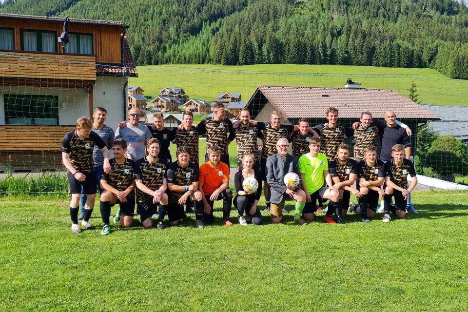 Eine Gruppe von Fußballspielern steht auf einem grünen Feld vor einem sportlichen Hintergrund. Sie tragen einheitliche Trikots und posieren gemeinsam für ein Gruppenfoto. | © STR Brodjäger
