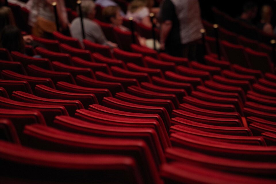 Ein Konzertsaal mit roten Sitzen. Im Hintergrund sind einige Menschen zu sehen. | © pixabay