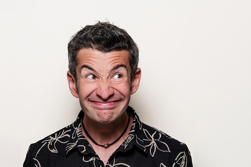 Eine Mikrofon auf einem Stativ vor einer Ziegelwand mit dem Wort "Comedy" in grüner Neonbeleuchtung. Die Szene strahlt eine einladende Atmosphäre für Comedy-Auftritte aus. | © Stefan Gergely