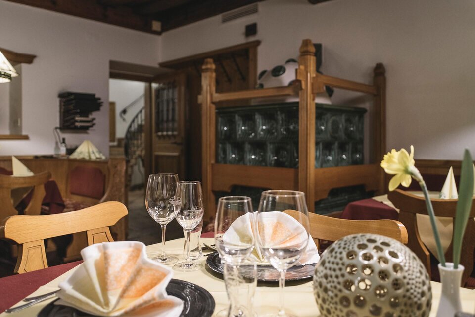 Ein stilvoll gedeckter Tisch in einem gemütlichen Restaurant. Im Hintergrund sind Holzmöbel und dekorative Elemente zu sehen. | © TV Gesäuse