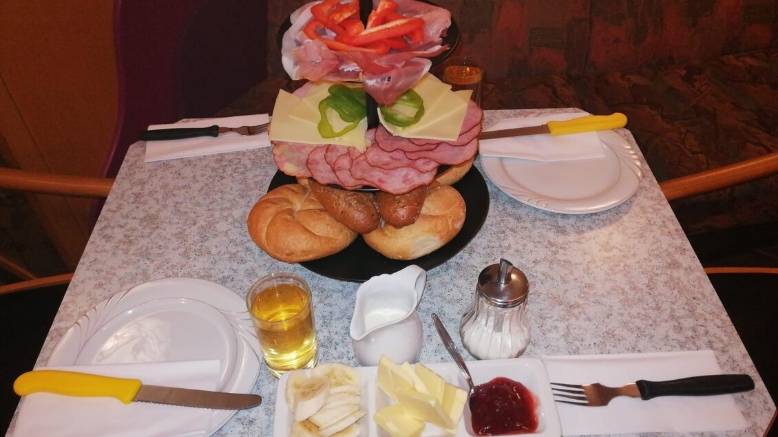 Ein Tisch mit einem großen Frühstückstablett. Es gibt Wurst, Käse, Brötchen und ein Glas Getränk. | © TV Murau