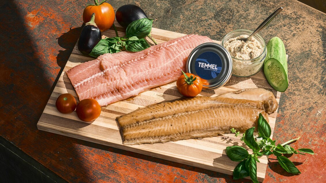 Ein Holzbrett mit frischem Fisch, darunter eine helle und eine dunkle Filetsorte. Umgeben von frischem Gemüse und einer Schüssel mit Aufstrich. | © Robert_Maybach