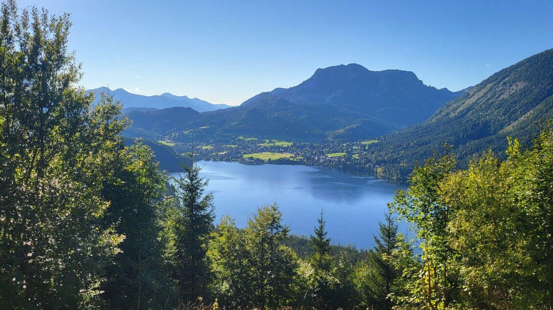 <p>Vom Bürgermeisterbankerl in Bad Aussee ist ein Blick auf die malerische Landschaft von Altaussee mit dem Altausseer See und den umliegenden Bergen möglich. Der Himmel ist strahlend blau und die Bäume umgeben die Szenerie.</p> | © TVB Ausseerland Salzkammergut