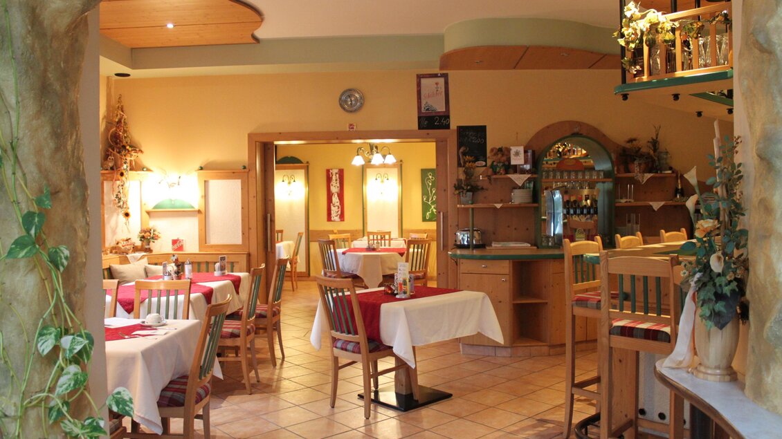 Ein gemütliches Restaurant mit mehreren Tischen und Stühlen. Die Wände sind warm gestaltet und es gibt eine kleine Bar im Hintergrund. | © Café Hotel Garni Thermenoase