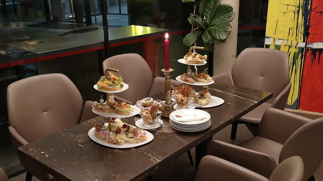 Ein schön gedeckter Tisch in einem modernen Raum. Auf dem Tisch stehen mehrere Etageren mit einer Auswahl an Gebäck und Snacks. | © Cafe Gande