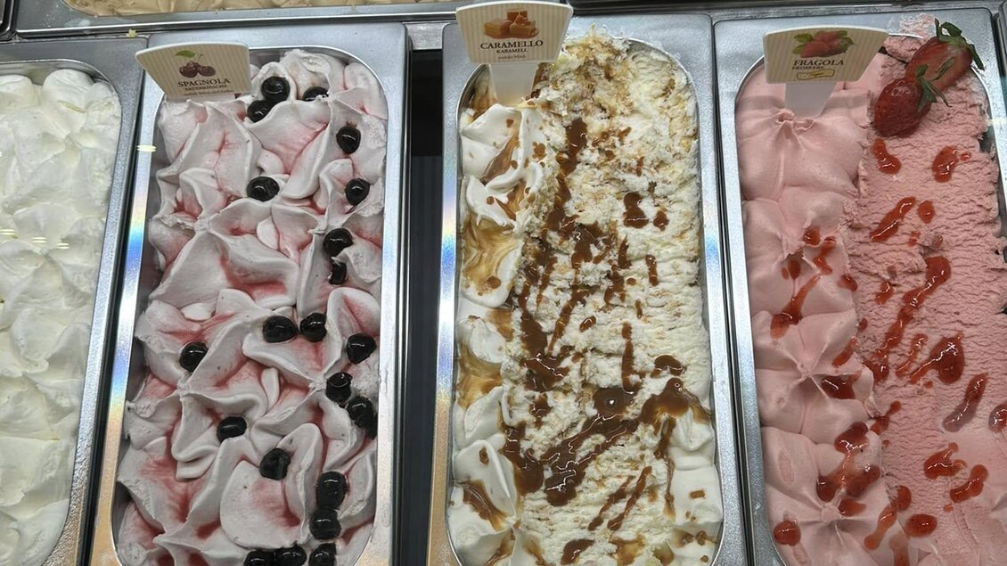 Ein Eisstand mit verschiedenen Sorten Eiscreme in bunten Farben. Die Behälter enthalten Geschmäcker wie Erdbeere, Vanille und Karamell. | © Cafe Gande