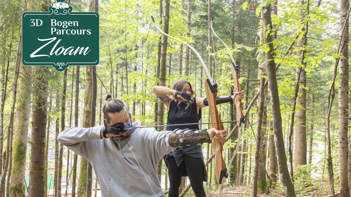 Zwei Personen schießen in einem Wald mit Bögen auf Ziele. Im Hintergrund sind hohe Bäume und ein Schild mit der Aufschrift "3D Bogen Parcours Zloam". | © www.zloam.at