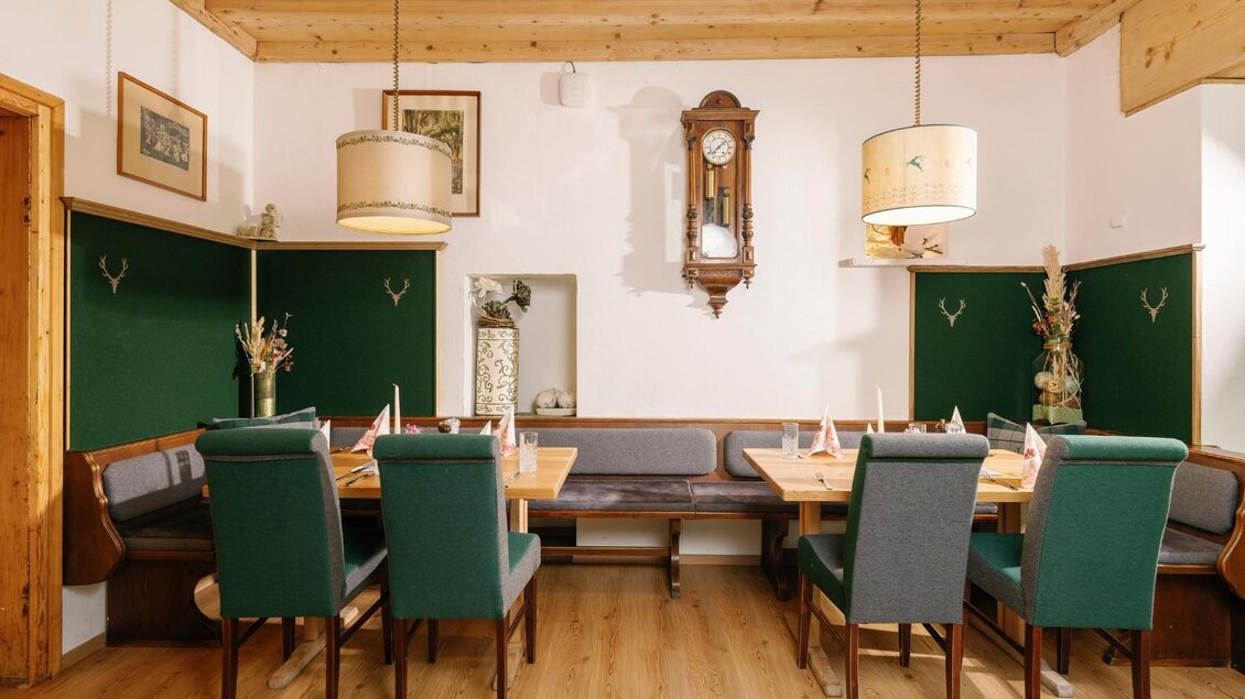 Ein gemütlicher Essbereich mit Holzboden und Holzdecke. Die Wände sind in warmen Farben gehalten und mit Pflanzen und Bildern dekoriert. | © Gasthaus Stöckl