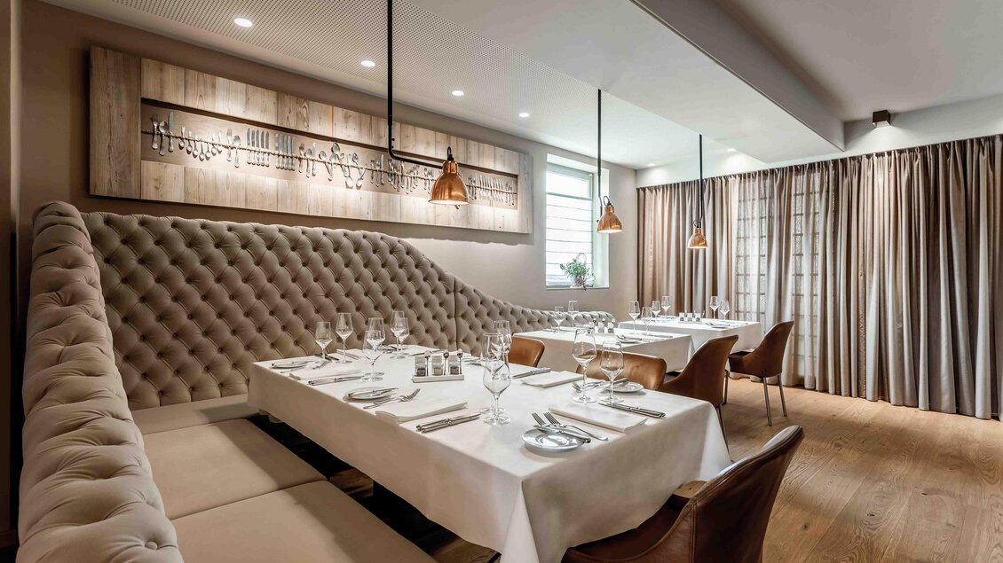 Ein elegantes Restaurant mit modernem Interieur. Der Tisch ist festlich gedeckt und die Wände sind mit sanften Farbtönen und dekorativen Elementen gestaltet.