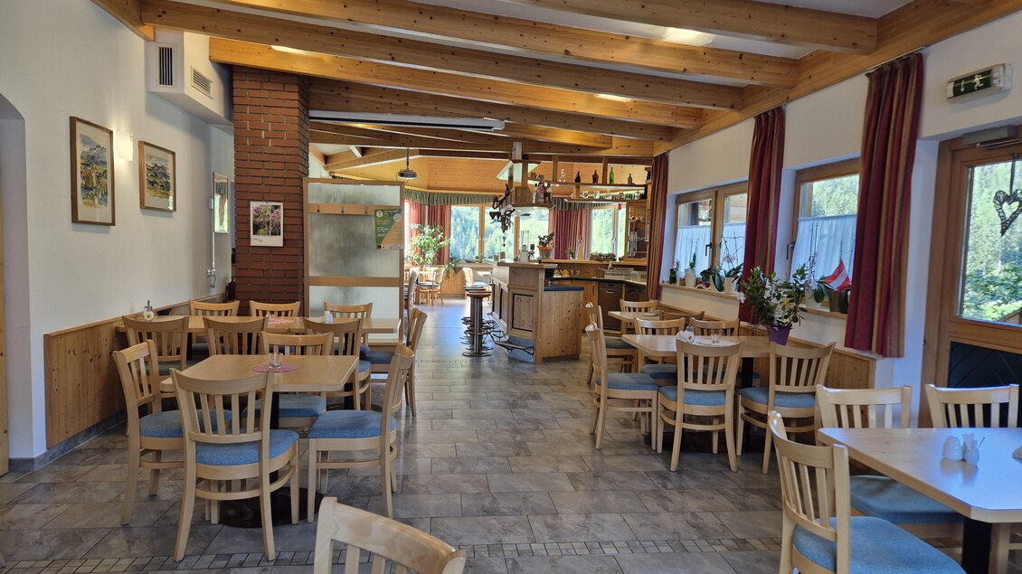 Ein gemütliches Restaurant mit Holztischen und Stühlen. Durch große Fenster strömt Tageslicht in den Raum. | © TV Murau