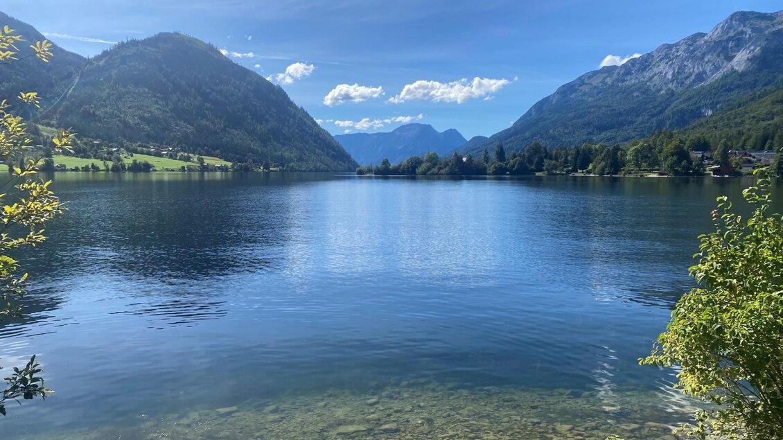 Der ruhige Grundlsee aus Richtung Gößl fotografiert, umgeben von den Bergen des Ausseerland Salzkammergutes. Der Himmel ist klar und blau, und das Wasser spiegelt die wunderschöne Landschaft wider. | © Bettina Scheck