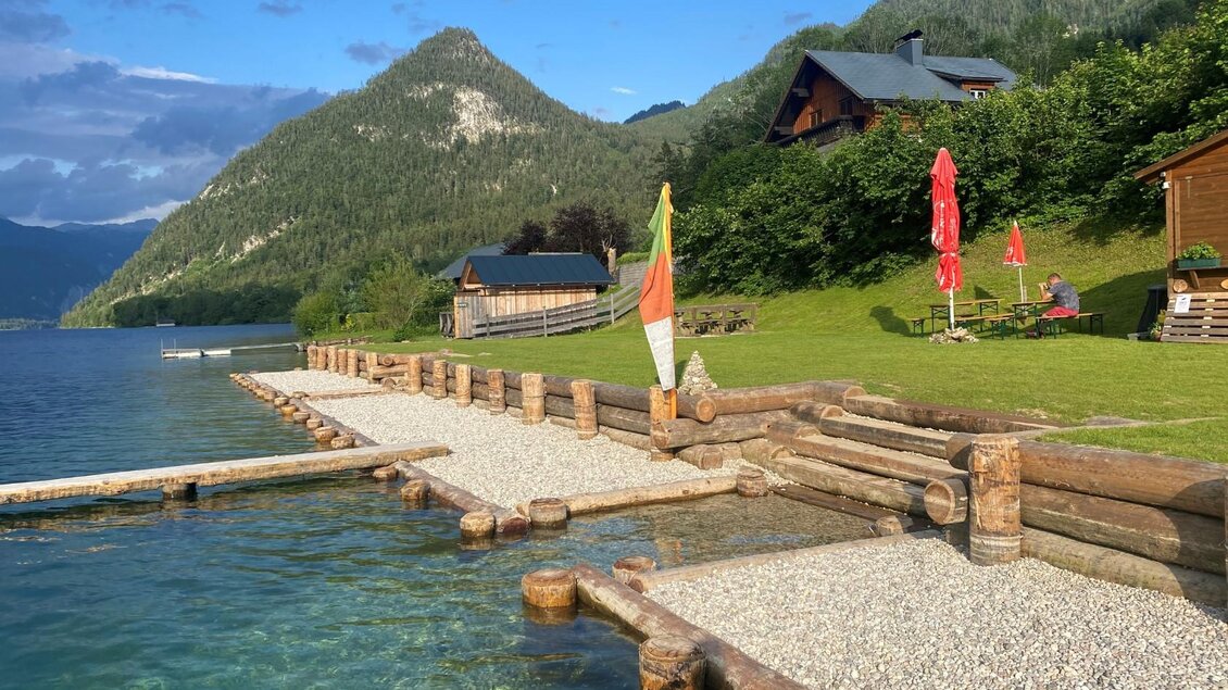 Das Freibad auf der Au am Südufer des malerischen Grundlsees mit einem Steg aus Holz und einer Liegewiese. Im Hintergrund sind die Berge des Ausseerland Salzkammergutes zu sehen. | © Bettina Scheck