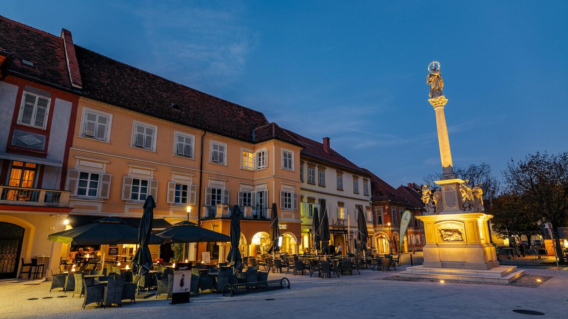 Beleuchtete Mariensäule am Hauptplatz von Bad Radkersburg mit Gastgärten und historischer Altstadt bei Abendstimmung. | © Zehnerhaus Bad Radkersburg