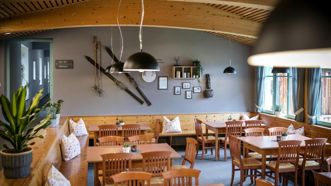 Ein gemütliches Restaurant mit Holzmöbeln und einer warmen Atmosphäre. Die Wände sind mit Skiausrüstung und Bildern dekoriert. | © Jufa Hotel Eisenerz