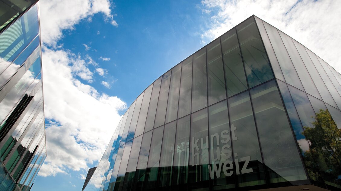 Ein modernes Gebäude mit großen Glasfassaden und einem klaren blauen Himmel. Die Wolken verleihen der Szene einen lebhaften Kontrast. | © Kunsthaus Weiz