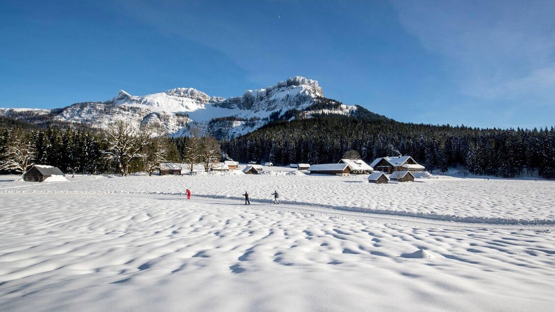 <p>Die verschneite Berglandschaft von Altaussee mit Hütten und Bäumen. Im Hintergrund erhebt sich das Gebirge des Losers unter einem klaren blauen Himmel.</p> | © TVB Ausseerland - Salzkammergut-Tom Lamm