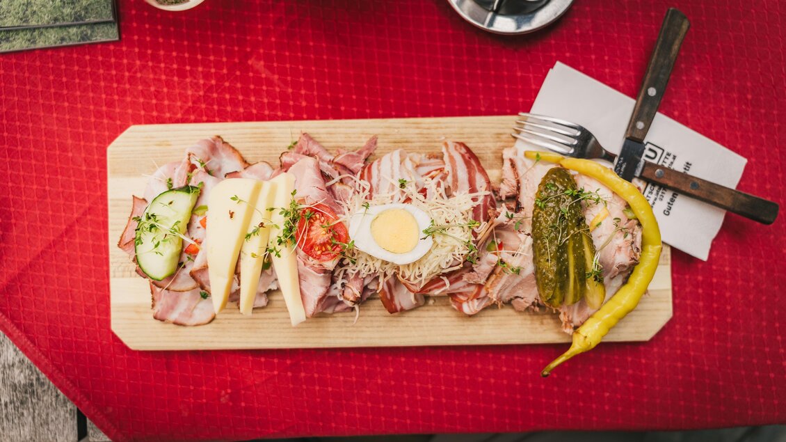 Eine Holzplatte mit verschiedenen Wurstsorten, Käse und frischem Gemüse. Dazu ein gekochtes Ei und Essiggurken. | © Oststeiermark Tourismus