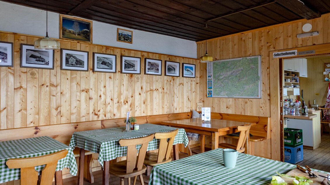 Ein gemütliches Restaurant mit Holzwänden und karierten Tischdecken. An den Wänden hängen Bilder und eine Karte ist sichtbar. | © TV Erzberg-Leoben