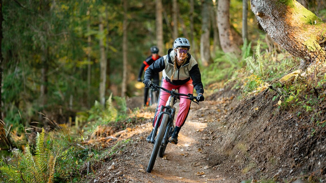 <p>Eine Radfahrerin ist am Augst Singletrail, umgeben von grünen Bäumen am Loser in Altaussee, unterwegs. Im Hintergrund ist ein weiterer Radfahrer zu sehen.</p> | © Loser Bergbahnen Altaussee/K. Steinegger