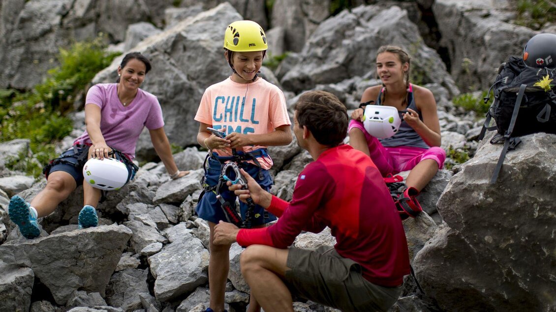 <p>Eine Gruppe von vier Personen sitzt auf Felsen am Loser in Altaussee. Sie haben Kletterausrüstung dabei und bereiten sich auf das Klettern vor.</p> | © TVB Ausseerland - Salzkammergut-Tom Lamm