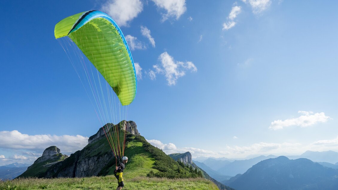 <p>Ein Paraglider steht auf einer grünen Wiese am Loser in Altausee. Der Himmel ist blau mit wenigen Wolken und die Berglandschaft liegt ihm zu Füßen.</p> | © Loser Bergbahnen Altaussee/F. Loitzl