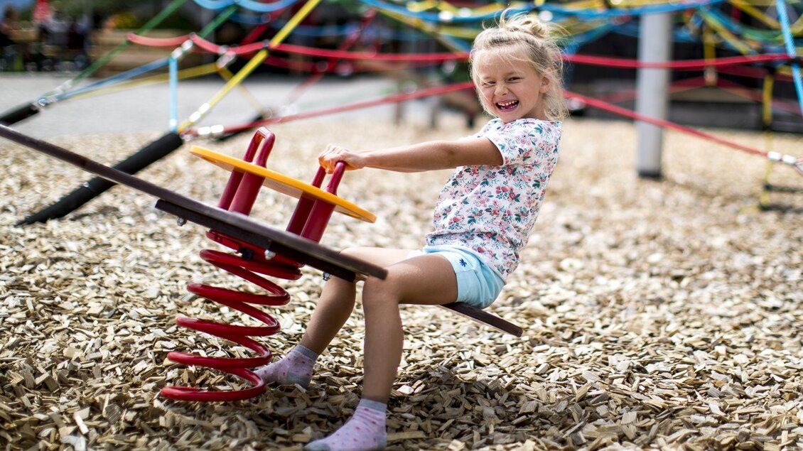 <p>Ein aufgewecktes Mädchen spielt auf einer Federwippe auf dem Spielplatz neben der Loseralm in Altaussee. Der Boden ist mit Holzspänen bedeckt, und im Hintergrund sind die bunten Seile des Klettergerüsts sichtbar.</p> | © TVB Ausseerland - Salzkammergut-Tom Lamm