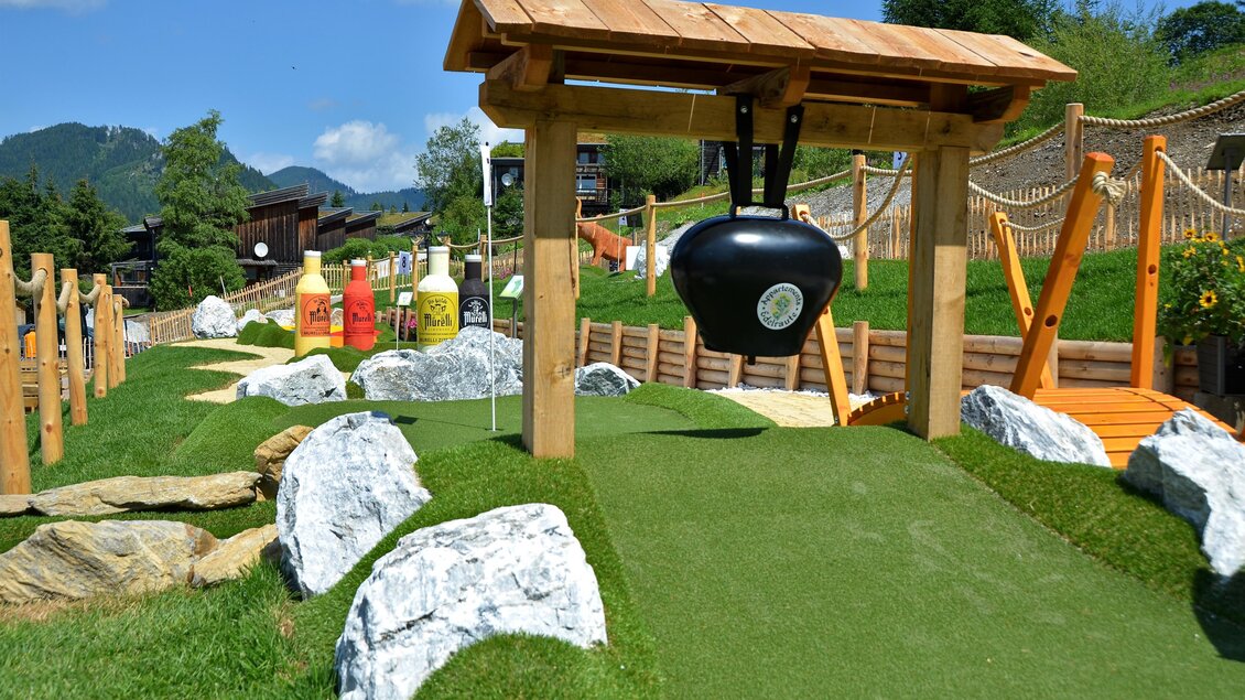 Ein Minigolfplatz mit einer Kuppel und einem herausfordernden Hindernis. Grüne Wiesen und dekorative Steine umgeben die Spielbahnen. | © Mountain Adventure Golf