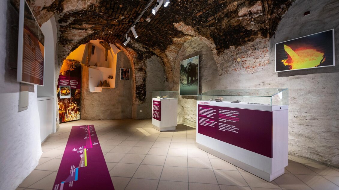 Ein historischer Ausstellungsraum mit Gewölbedecken. Glaskästen präsentieren Exponate und informative Tafeln an den Wänden. | © Stadtgemeinde Kapfenberg
