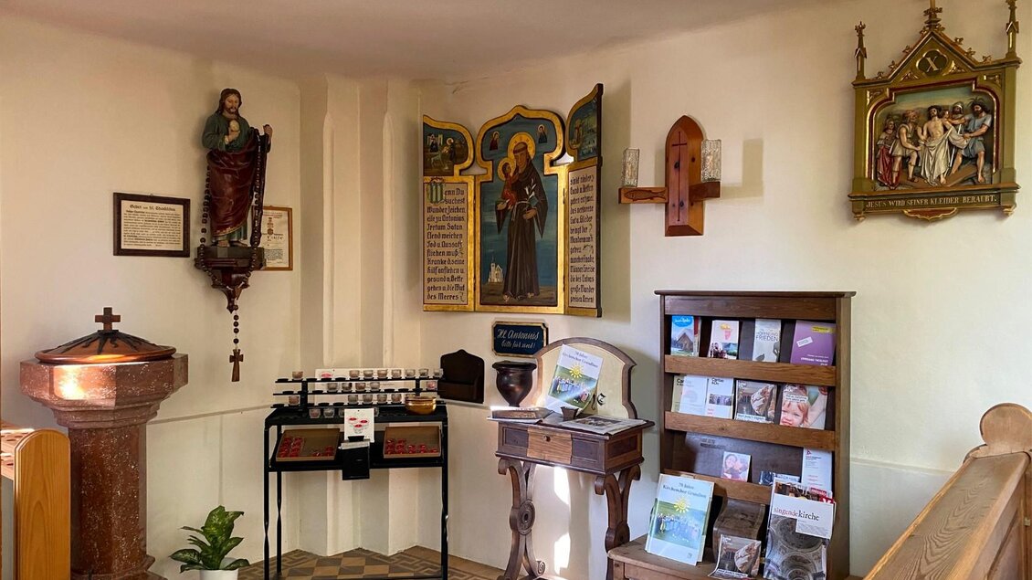 Ein Innenraum mit religiösen Statuen und Kunstwerken. Auf einem Tisch stehen Broschüren und Pflegeartikel bereit. | © Bettina Scheck