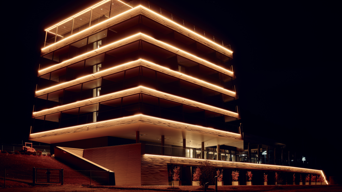 Ein modernes Gebäude mit leuchtenden Lichträndern bei Nacht. Die Fassade ist elegant und einladend gestaltet. | © Tauroa GmbH