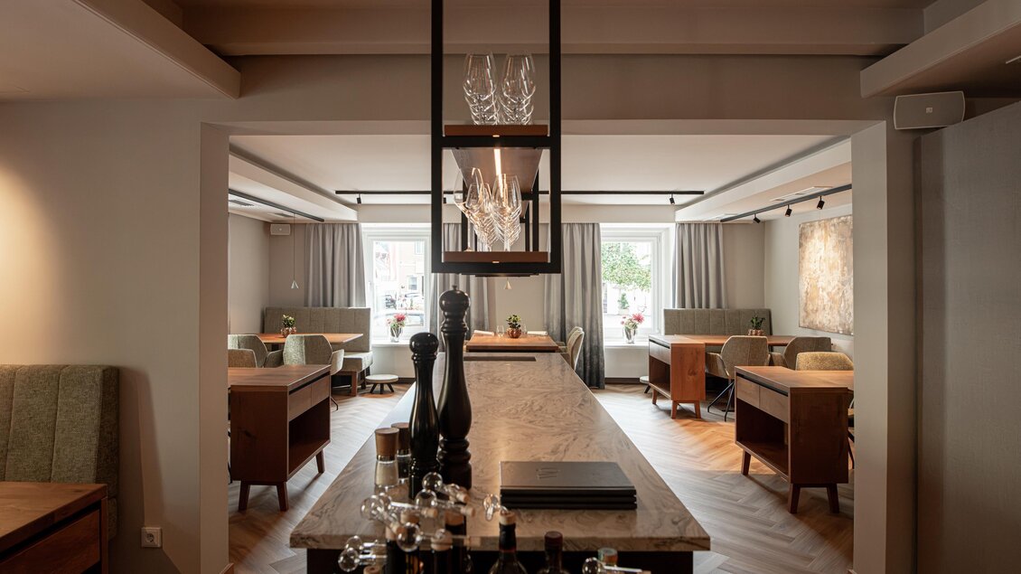 Blick über die zentrale Theke in den Gastraum des Restaurants Wörgötter in Ligist mit Holztischen und gepolsterten Sitzbänken | © Die Abbilderei
