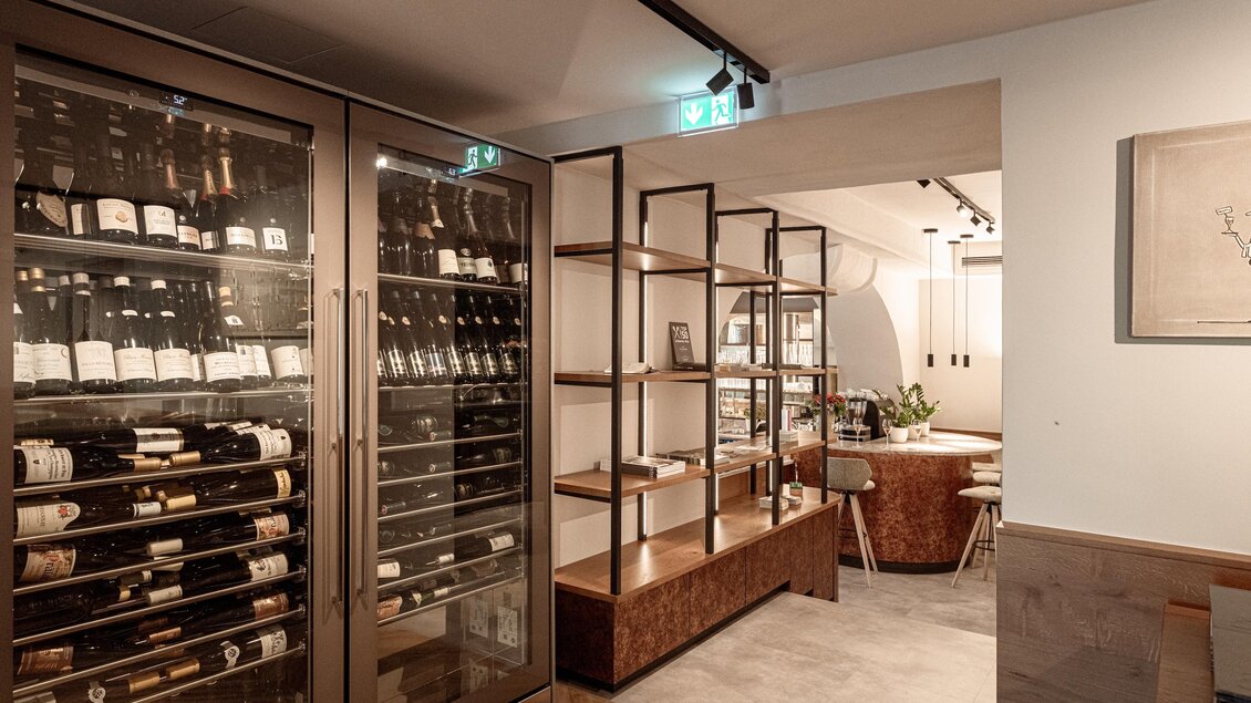 Zwei große Weinkühlschränke im Restaurant Wörgötter in Ligist neben offenen Holzregalen und einem Barbereich mit Hockern | © Die Abbilderei