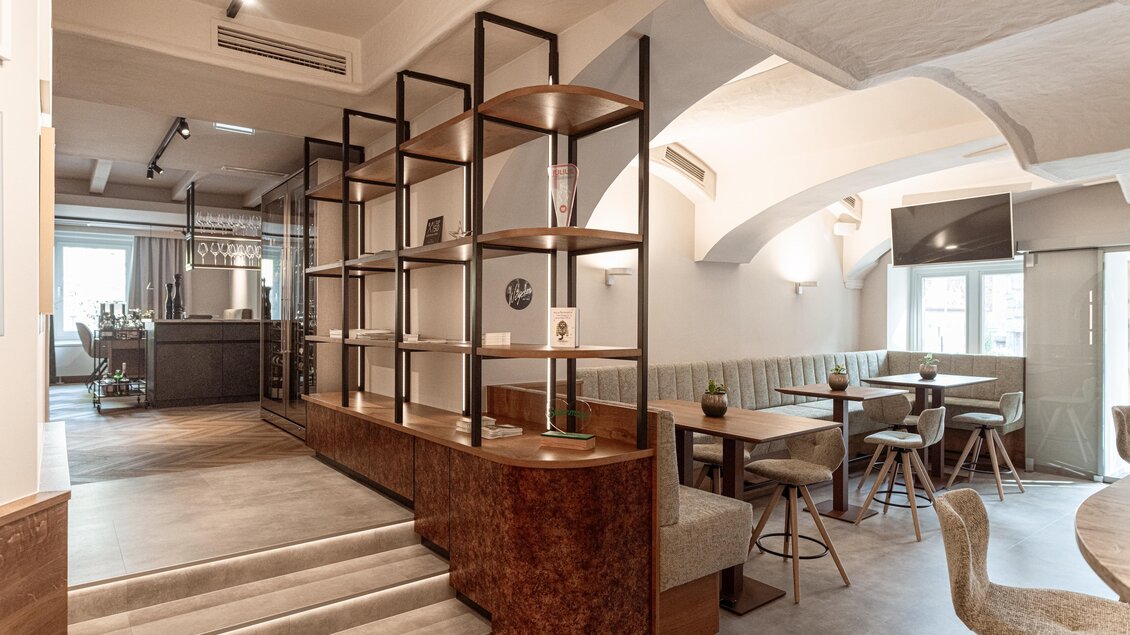 Sitzbereich im Restaurant Wörgötter in Ligist mit gepolsterten Bänken, Holztischen, offenen Regalen und Gewölbedecke | © Die Abbilderei